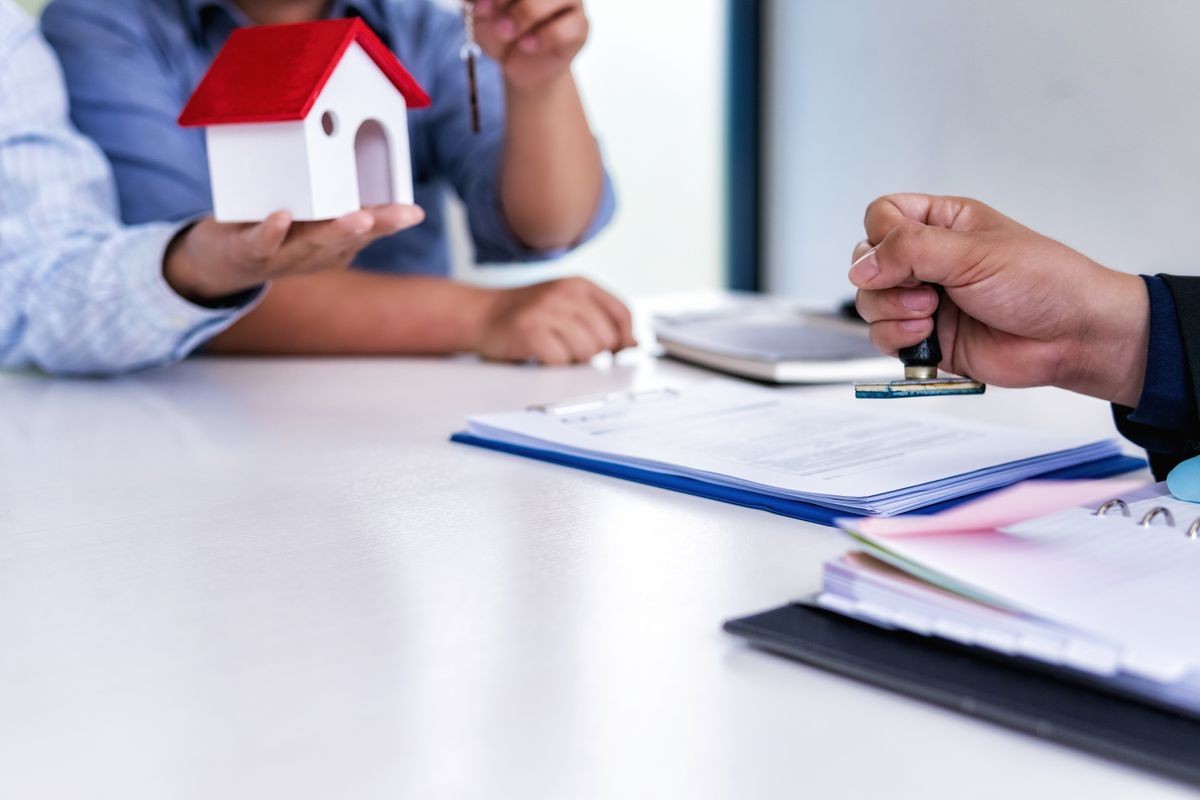 Business man sitting with hand holding stamp important contract Insurance documents for house and family in office.